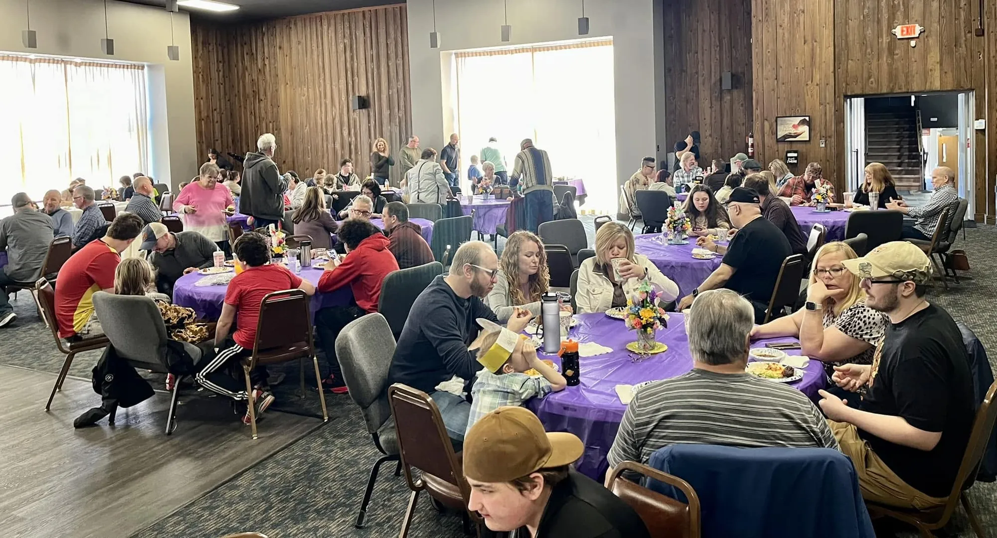 Rush Church members sharing a meal together at round tables in the fellowship hall