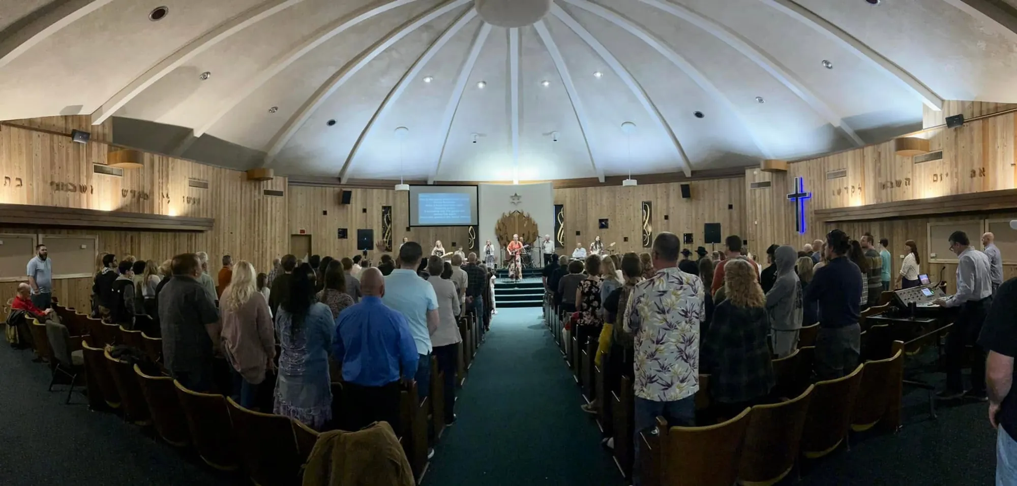 The Rush Church congregation standing in worship, seen from the back of the sanctuary facing the stage and band