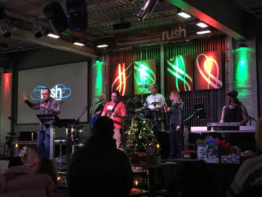 A band leading worship in the Rush Youth room under colorful stage lighting